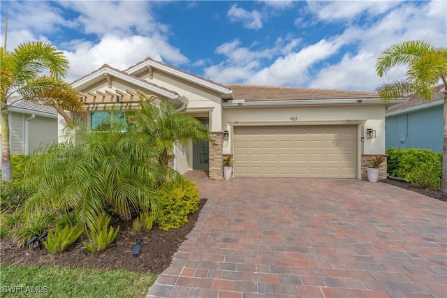 view of front of property with stone siding, decorative driveway, an attached garage, and stucco siding