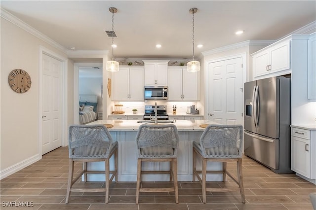 kitchen featuring a center island with sink, appliances with stainless steel finishes, hanging light fixtures, and white cabinetry