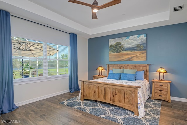 bedroom featuring visible vents, a raised ceiling, and dark wood-style flooring