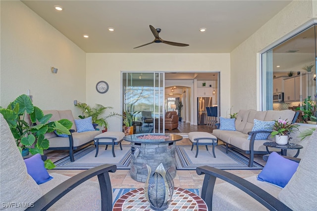 view of patio / terrace with a ceiling fan and an outdoor living space with a fire pit