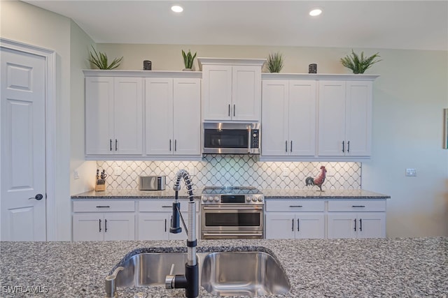 kitchen with appliances with stainless steel finishes, white cabinets, and a sink