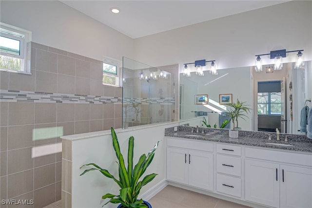 full bath featuring double vanity, plenty of natural light, a walk in shower, and a sink