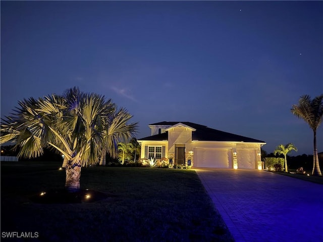 view of front of home with decorative driveway, an attached garage, and stucco siding