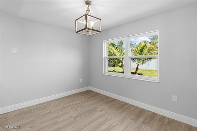 empty room with an inviting chandelier and light hardwood / wood-style flooring