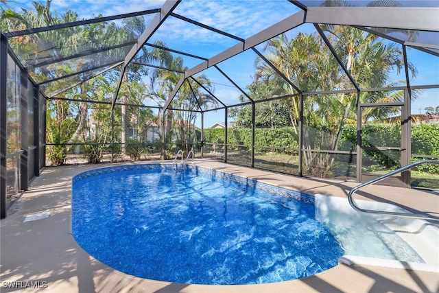 view of swimming pool featuring glass enclosure and a patio area