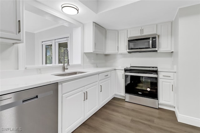 kitchen with sink, crown molding, dark wood-type flooring, appliances with stainless steel finishes, and white cabinets