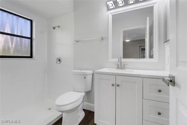 bathroom with vanity, toilet, wood-type flooring, and a tile shower