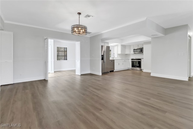 unfurnished living room featuring hardwood / wood-style flooring, ornamental molding, sink, and a notable chandelier