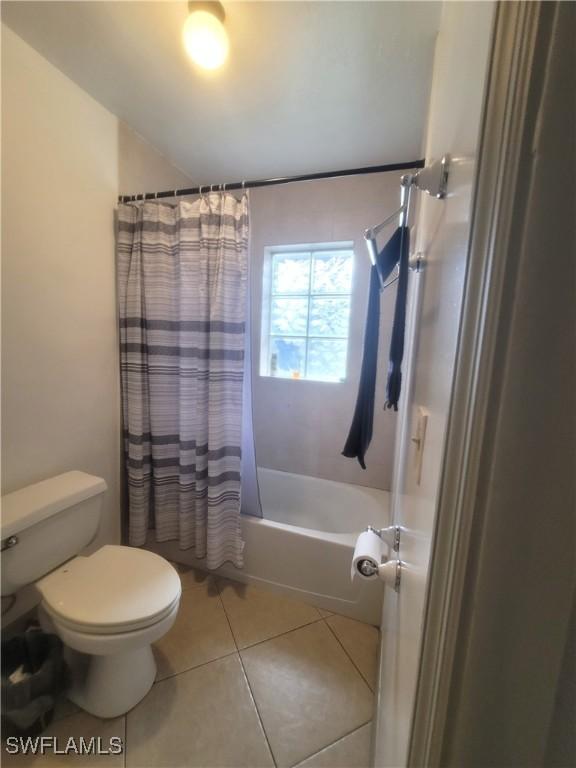 bathroom with tile patterned flooring, toilet, and shower / bath combo with shower curtain