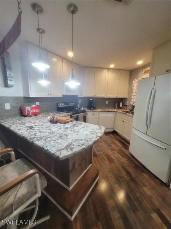 kitchen with decorative light fixtures, white cabinets, kitchen peninsula, light stone countertops, and white appliances