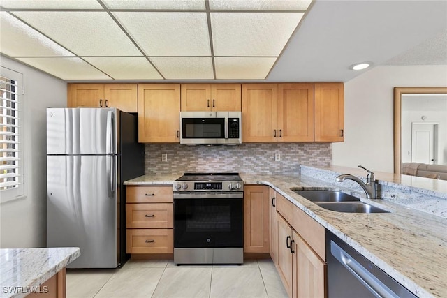 kitchen with light stone countertops, appliances with stainless steel finishes, decorative backsplash, and a sink