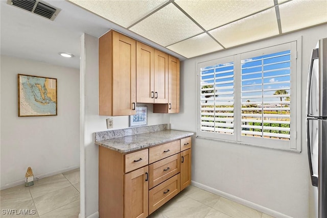 kitchen with freestanding refrigerator, visible vents, baseboards, and light tile patterned flooring