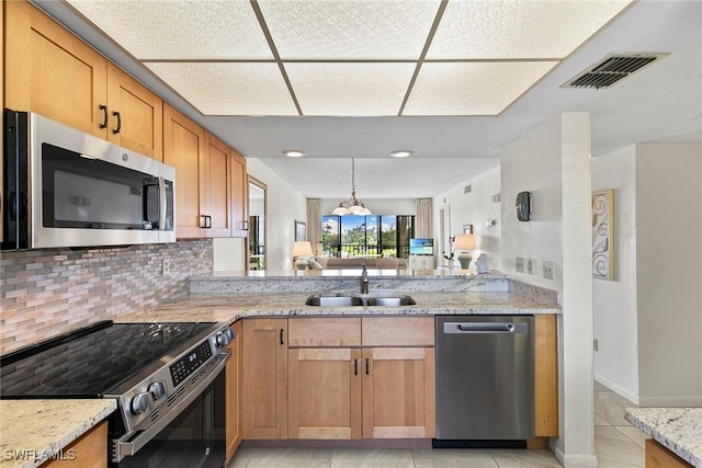 kitchen with appliances with stainless steel finishes, a sink, visible vents, and light stone countertops