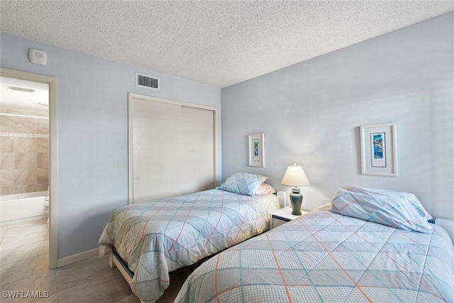 bedroom featuring baseboards, visible vents, ensuite bath, a textured ceiling, and a closet