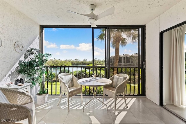 sunroom with a ceiling fan and a water view