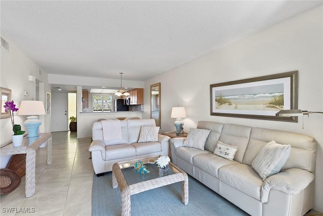 living room with visible vents, a textured ceiling, and light tile patterned floors