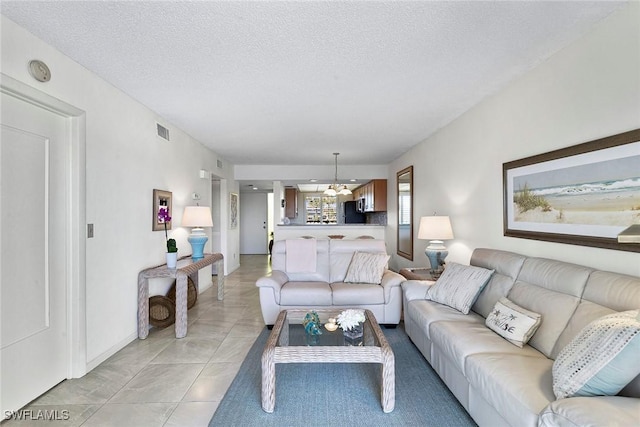 living room with a textured ceiling, light tile patterned floors, and visible vents