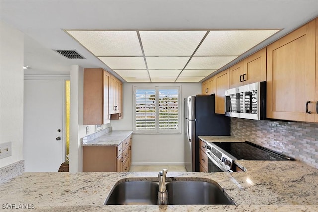 kitchen featuring light stone counters, visible vents, appliances with stainless steel finishes, light brown cabinets, and a sink