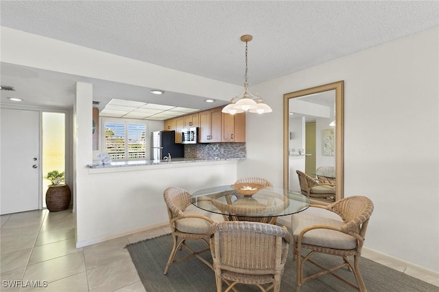 dining area with light tile patterned flooring, visible vents, baseboards, and a textured ceiling