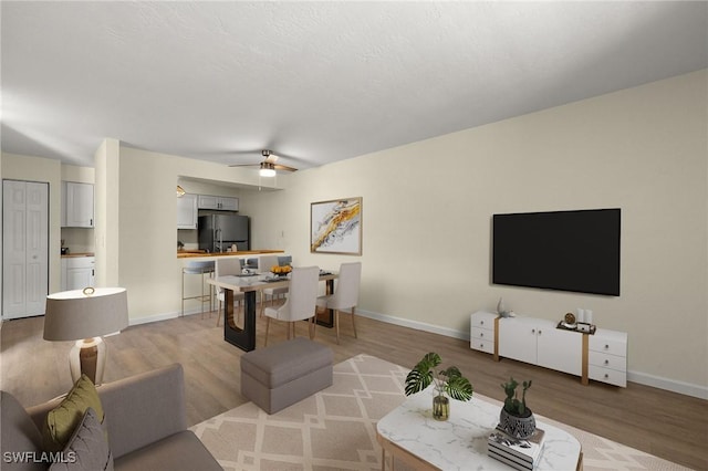 living room featuring ceiling fan, hardwood / wood-style floors, and a textured ceiling
