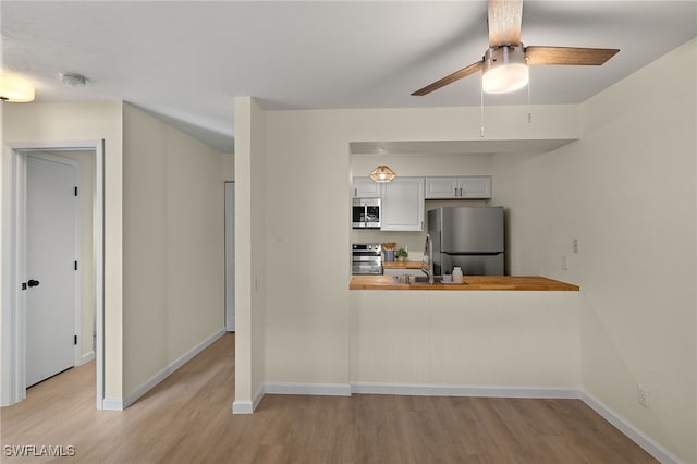 kitchen with sink, wooden counters, light hardwood / wood-style flooring, appliances with stainless steel finishes, and ceiling fan