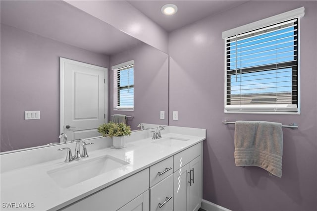 bathroom with double vanity, baseboards, and a sink