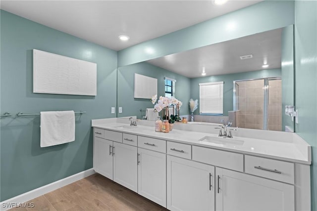 full bath with baseboards, wood finished floors, a sink, and a shower stall