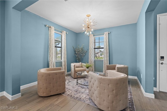 sitting room featuring a notable chandelier, baseboards, and wood finished floors