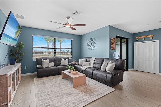 living room featuring a ceiling fan, visible vents, baseboards, and wood finished floors