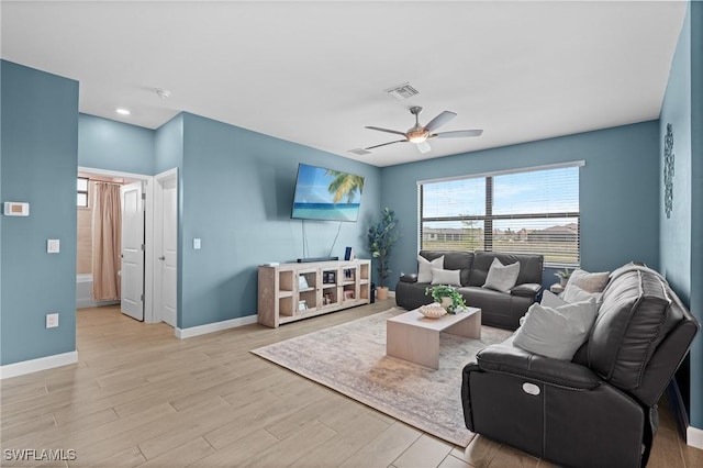 living area with baseboards, light wood-type flooring, visible vents, and a ceiling fan