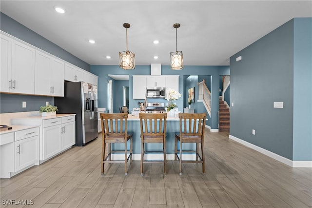 kitchen with appliances with stainless steel finishes, light countertops, light wood-type flooring, and white cabinets