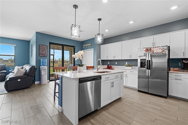 kitchen with stainless steel appliances, a wealth of natural light, light countertops, open floor plan, and a sink