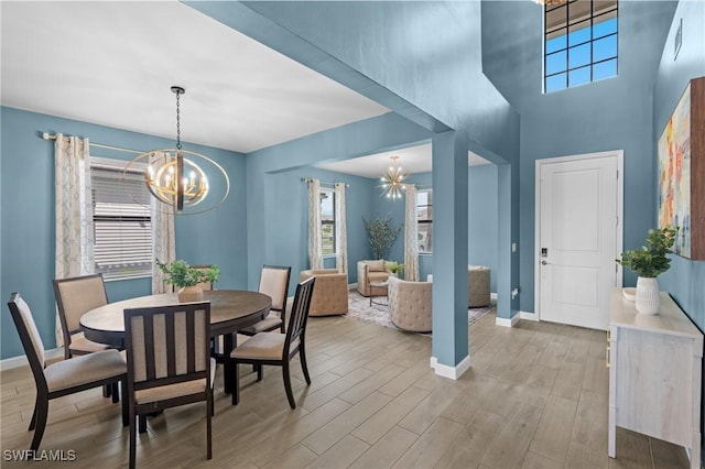 dining room featuring baseboards, light wood finished floors, and a notable chandelier