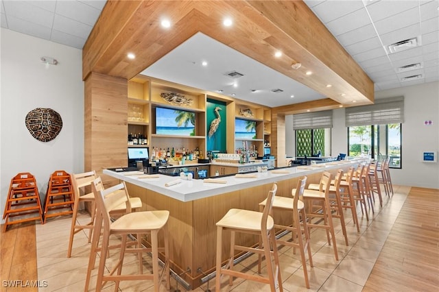 bar featuring a community bar, beamed ceiling, visible vents, and light wood-style floors