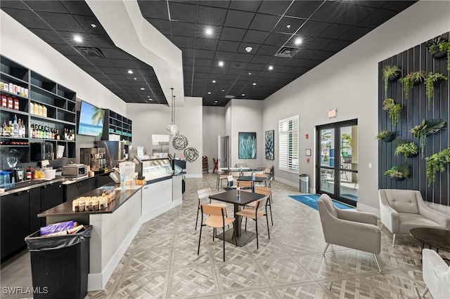 dining room featuring a community bar, a high ceiling, visible vents, and baseboards