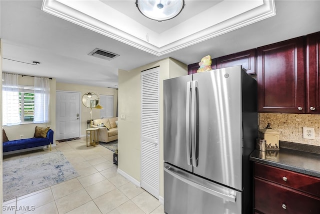 kitchen featuring light tile patterned flooring, stainless steel fridge, backsplash, and a tray ceiling