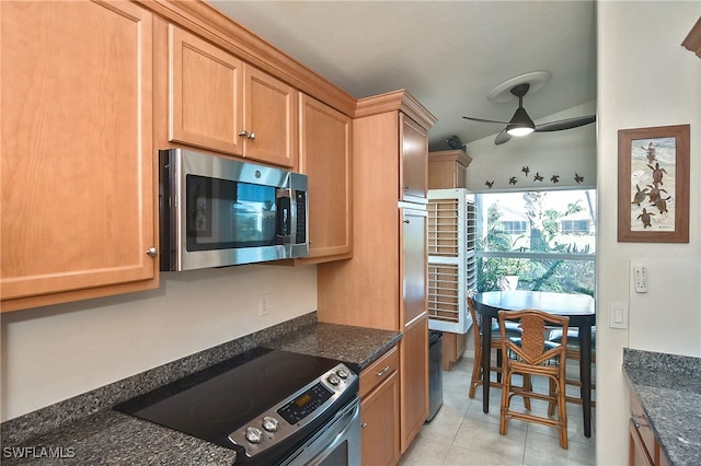 kitchen featuring appliances with stainless steel finishes, ceiling fan, dark stone counters, and light tile patterned floors