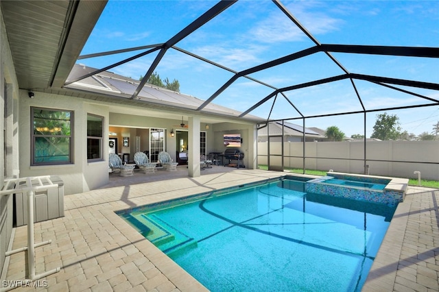 view of pool featuring glass enclosure, a pool with connected hot tub, fence, and a patio