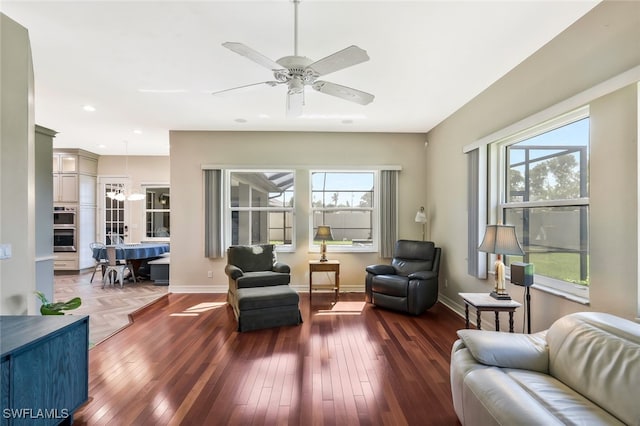 sitting room with a ceiling fan, dark wood-style flooring, and baseboards