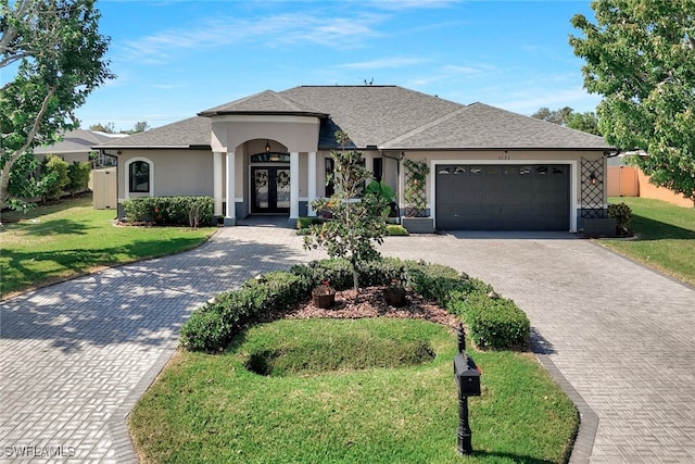 view of front of home with an attached garage, stucco siding, decorative driveway, and french doors