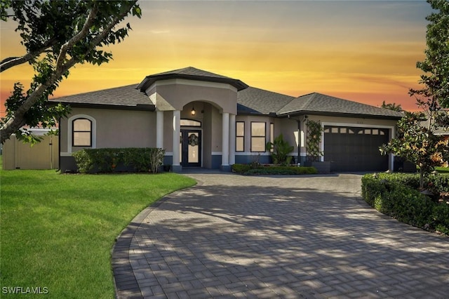 view of front of property with an attached garage, a front yard, decorative driveway, and stucco siding