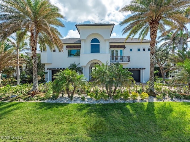 mediterranean / spanish home featuring an attached garage, a front yard, a balcony, and stucco siding