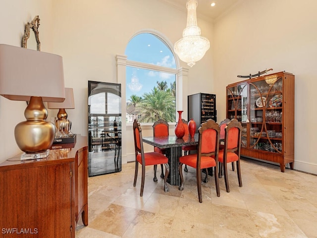 dining space featuring ornamental molding, baseboards, a notable chandelier, and a high ceiling