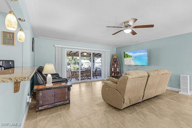 living room with light tile patterned floors, baseboards, ornamental molding, and a ceiling fan