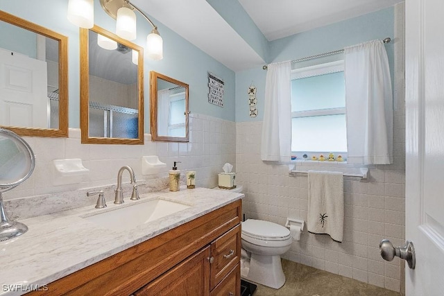 bathroom with toilet, walk in shower, tile walls, and vanity