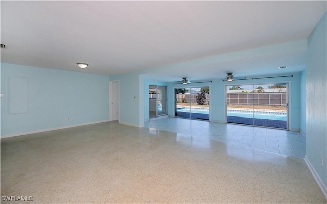 empty room with light speckled floor, visible vents, ceiling fan, and baseboards