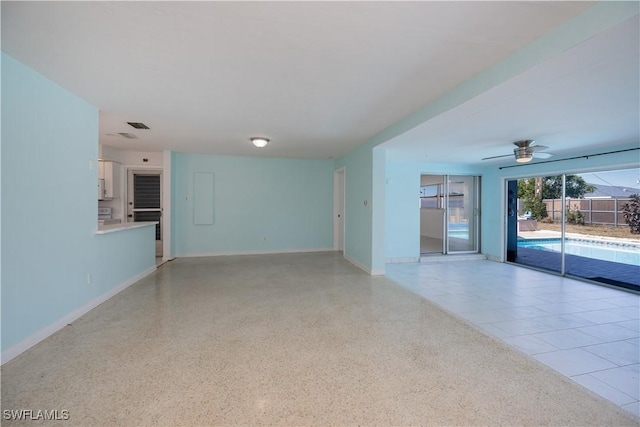 unfurnished living room featuring baseboards, light speckled floor, and a ceiling fan