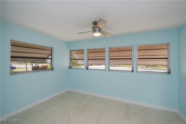 unfurnished room featuring baseboards, a ceiling fan, and speckled floor