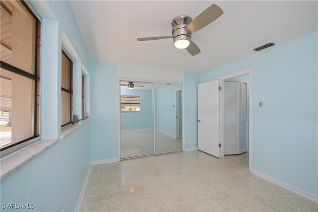 unfurnished bedroom with ceiling fan, baseboards, visible vents, and light speckled floor