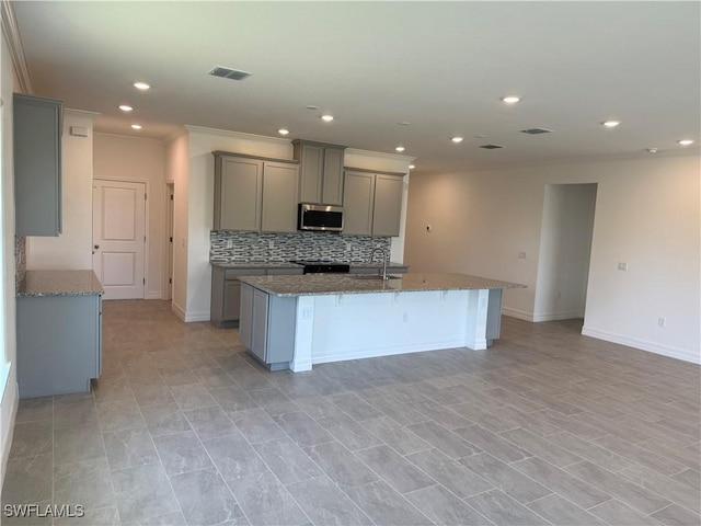 2211 Harbour Dr, Punta Gorda, FL 33983 - kitchen with stainless steel microwave, gray cabinets, black range oven, ornamental molding, and backsplash